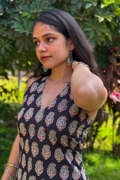 Woman wearing a paisley black patterned dress outdoors with greenery in the background