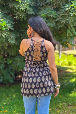 Woman wearing a paisley patterned top with a lace-up back in a garden setting
