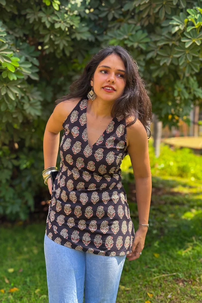 Woman wearing a paisley patterned top and jeans standing in a garden