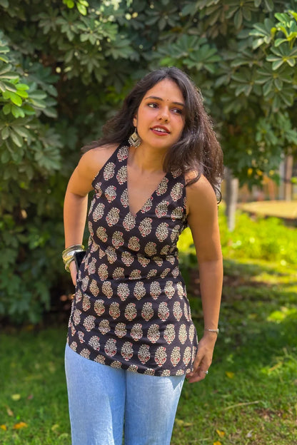 Woman wearing a paisley patterned top and jeans standing in a garden
