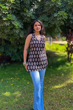 Woman wearing a paisley patterned top and blue jeans standing in a garden.