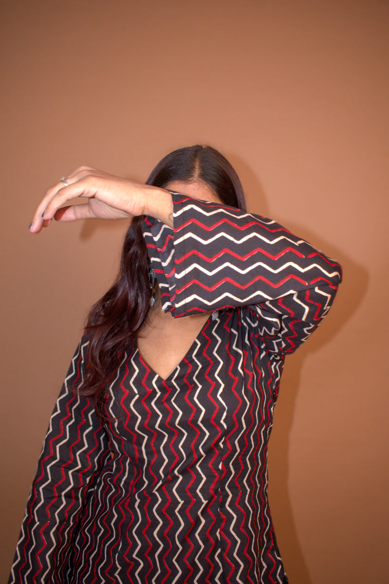 Person wearing a zigzag patterned shirt against a background