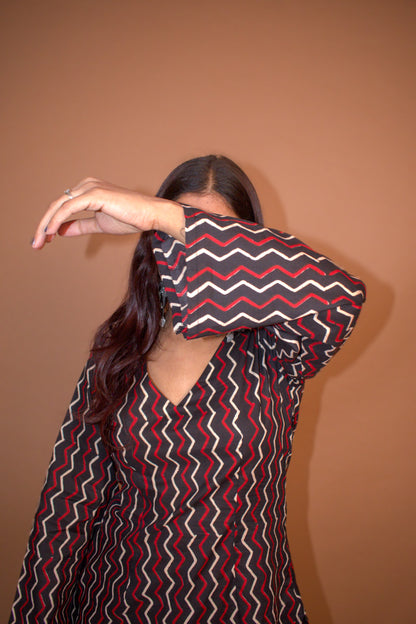Person wearing a zigzag patterned shirt against a background