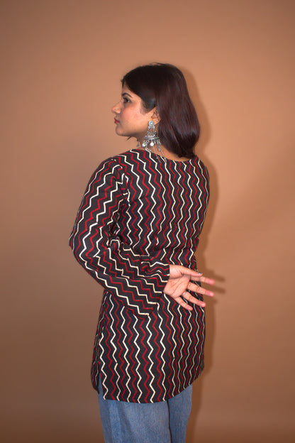 Woman wearing a zigzag top with a plain background