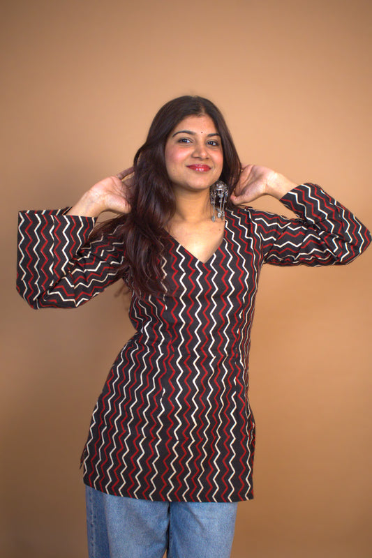 Woman wearing a zigzag patterned top against a beige background