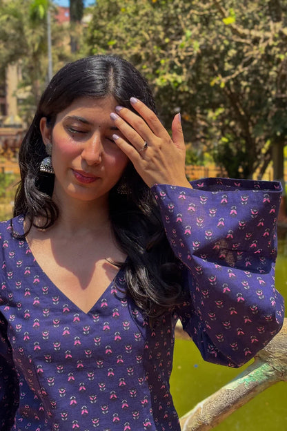 Woman wearing a jiva-blue patterned outfit with a blurred natural background 