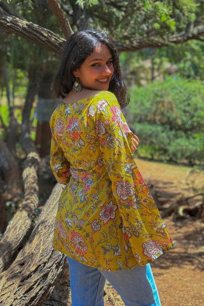 Woman wearing a jal-yellow floral dress standing outdoors near trees