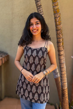 Woman in a leaf patterned top standing next to a palm tree