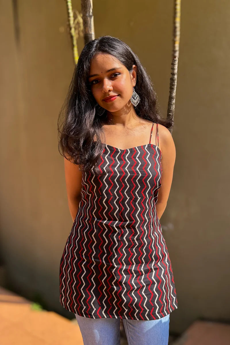 Woman wearing a zigzag patterned top standing against a neutral background