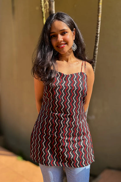 Woman wearing a zigzag patterned dress standing outdoors with a blurred background