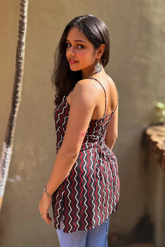 Woman wearing a zigzag patterned dress standing against a plain wall.