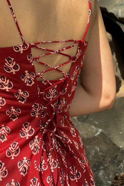 Butta Red patterned dress with criss-cross back detail on a blurred natural background