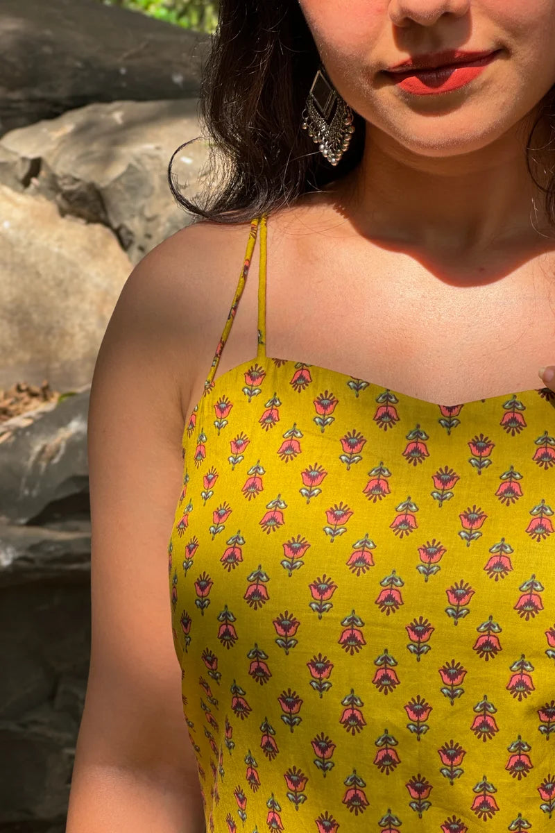 Person wearing a jiva-yellow dress with floral pattern outdoors