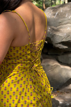 Person wearing a jiva-yellow floral dress with a rocky background