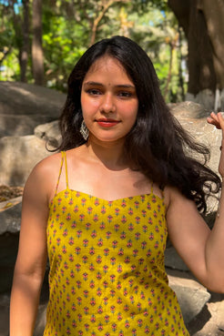 Woman in a jiva-yellow dress with floral pattern sitting outdoors