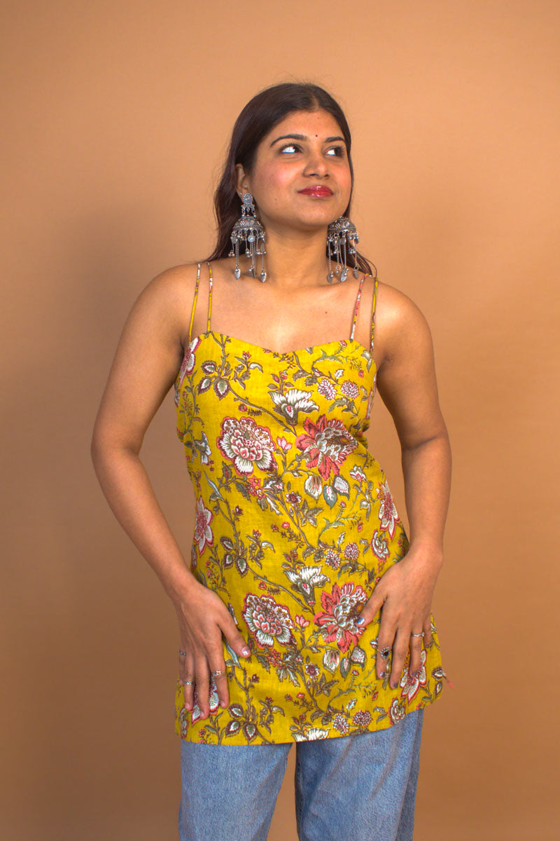 Woman wearing a jal-yellow floral top against a brown background