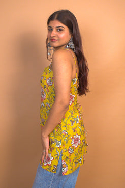 Woman wearing a jal-yellow floral sleeveless top against a beige background