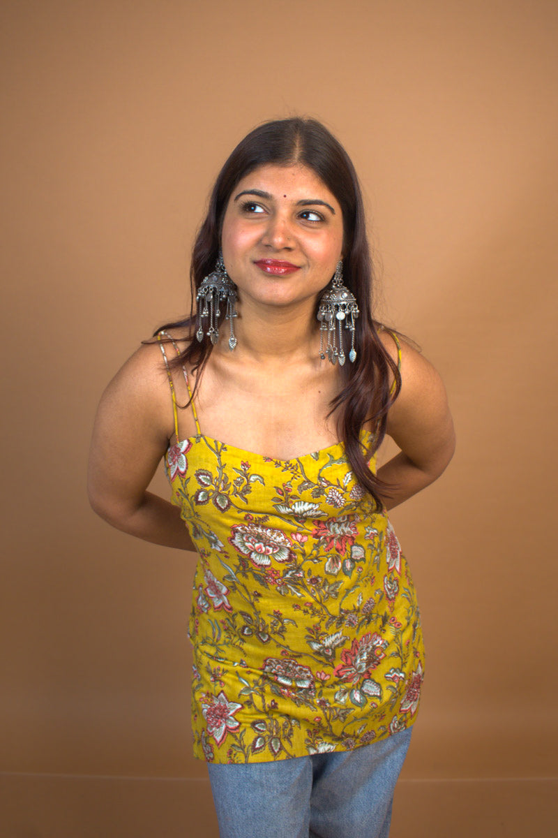 Woman wearing a jal-yellow floral top against a brown background