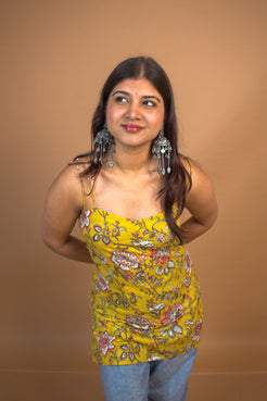 Woman wearing a jal-yellow floral top against a brown background