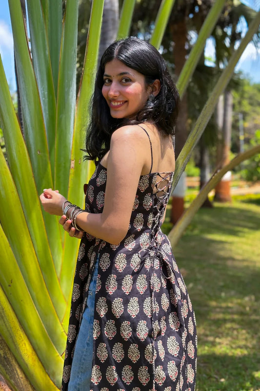 Woman in a paisley patterned dress standing among palm trees