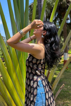 Woman in a paisley patterned dress standing among tall green plants
