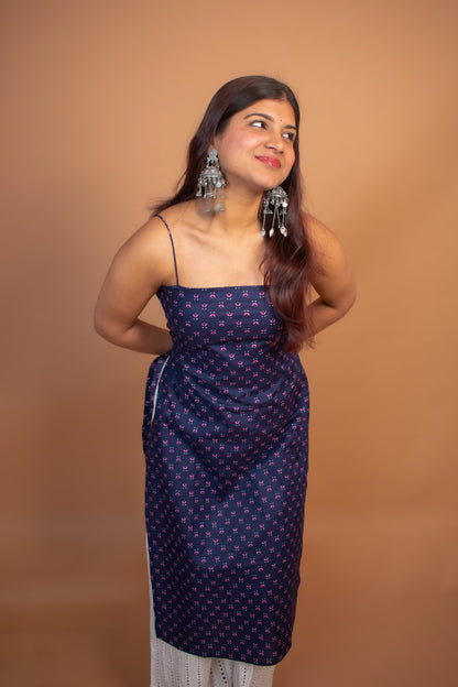 Woman wearing a jiva-blue dress with white patterns against a brown background