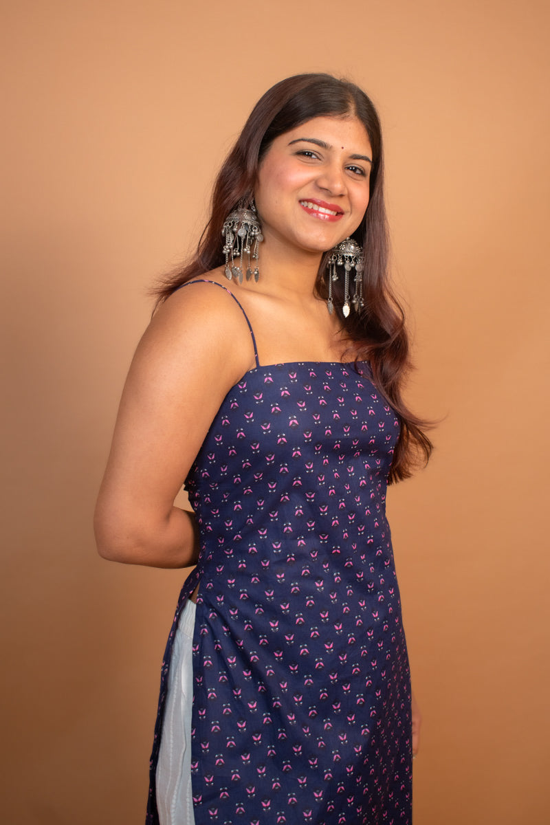 Woman wearing a jiva-blue dress with a pattern on a brown background