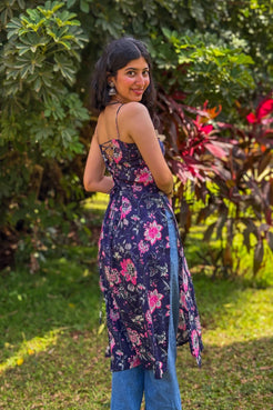 Woman wearing a jal-blue floral dress standing in a garden