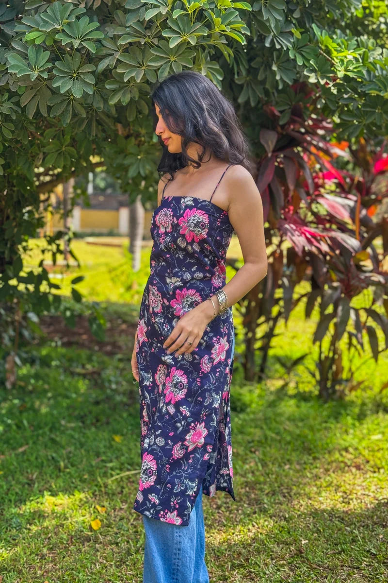 Woman in a jal-blue floral dress standing in a garden