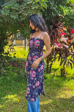 Woman in a jal-blue floral dress standing in a garden