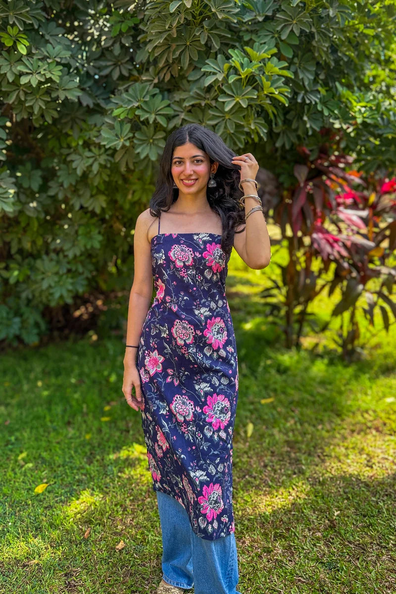 Woman in a jal-blue floral dress standing in a garden