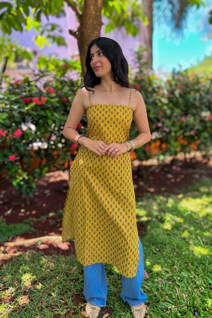 Woman wearing a jiva-yellow dress with a floral pattern in a garden setting