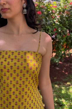 Woman wearing a jiva-yellow floral dress with a blurred garden background