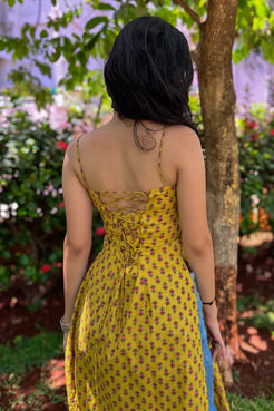 Woman in a jiva-yellow floral dress standing in a garden