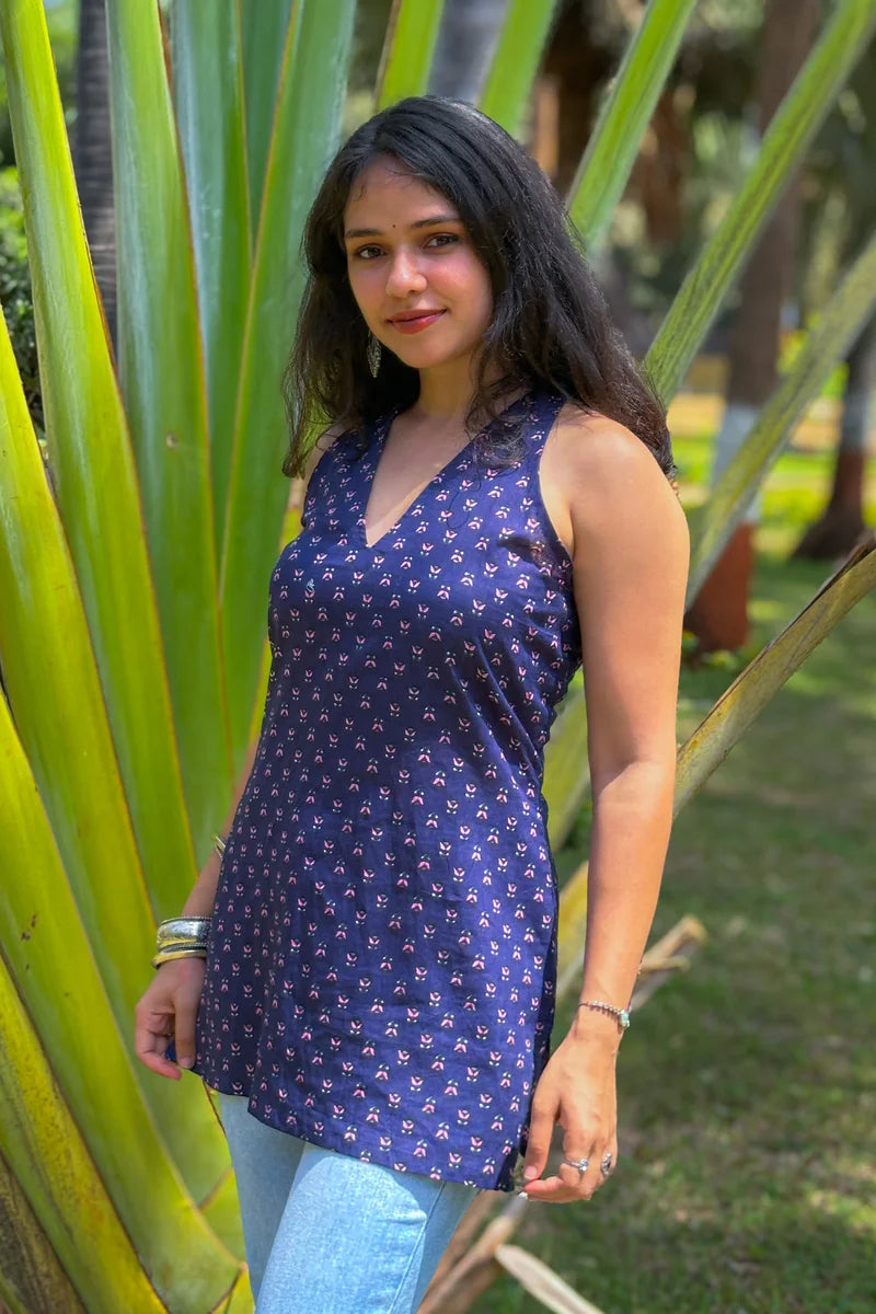 Woman in a jiva-blue patterned dress standing among tall green plants