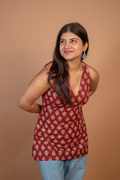 Woman wearing a butta red patterned top against a brown background