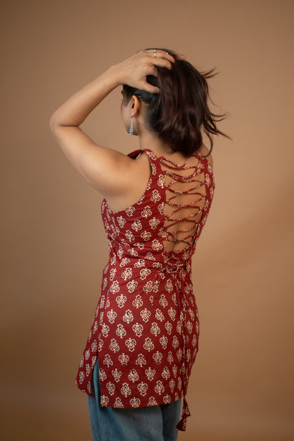 Woman wearing a butta red patterned top with cut-out design on a brown background