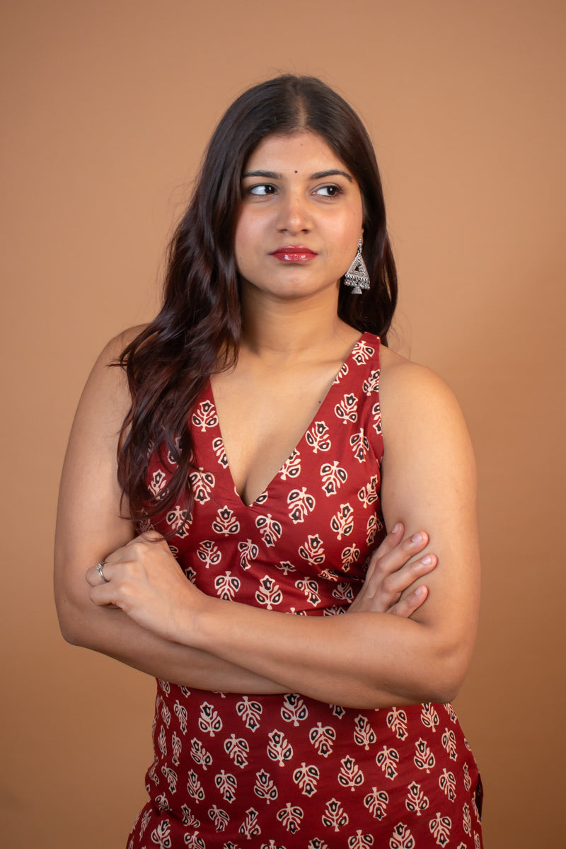 Woman wearing a butta red patterned dress against a brown background