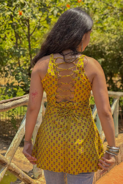 Woman wearing a jiva-yellow patterned top with a blurred natural background