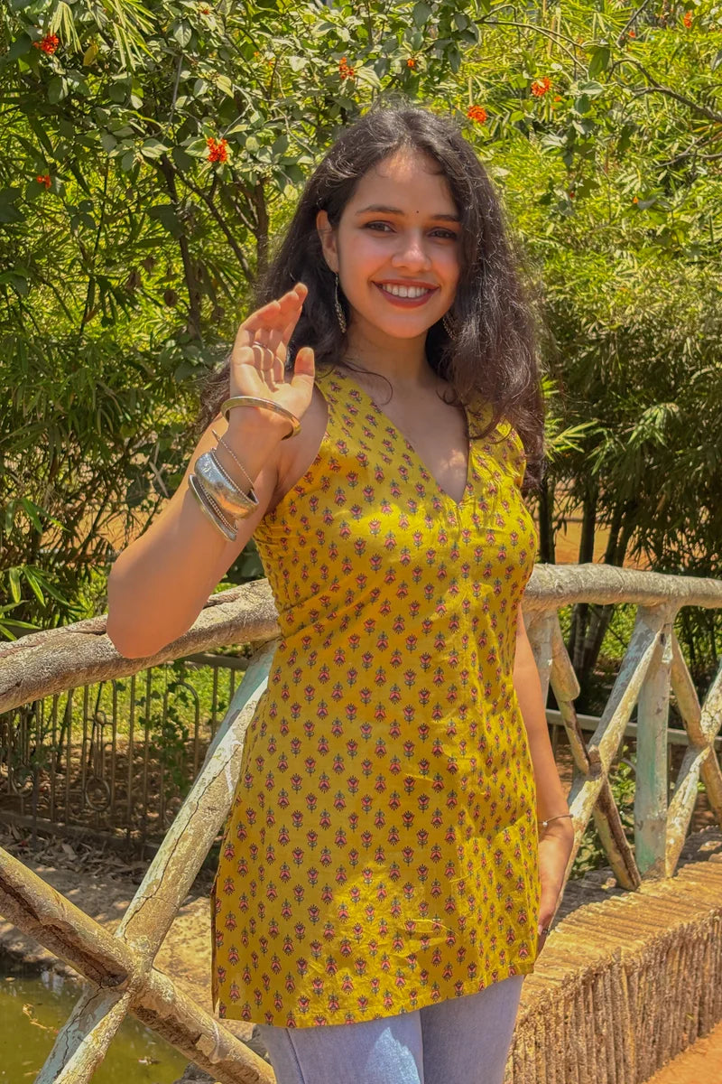 Woman in a jiva-yellow dress standing outdoors with greenery in the background