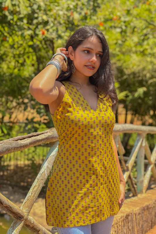 Woman wearing a jiva-yellow patterned dress standing outdoors with greenery in the background